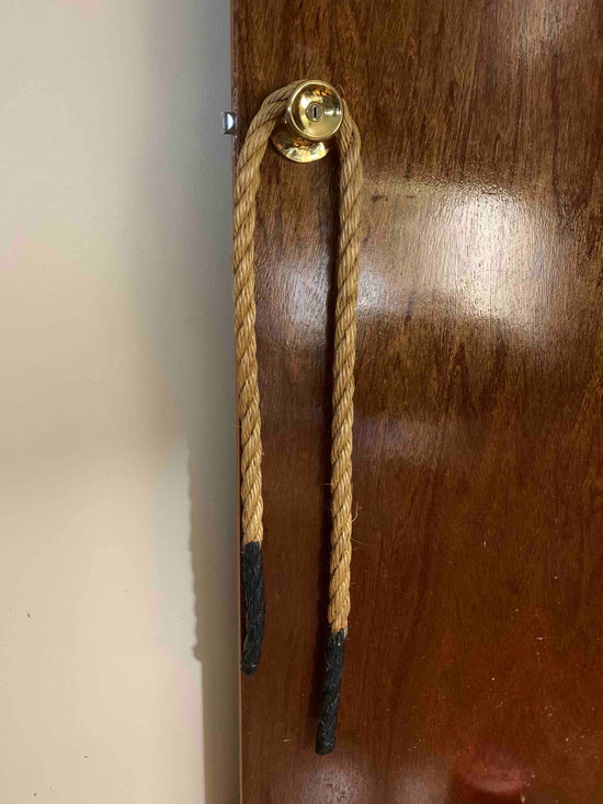 Hillbilly Backscratcher hanging on a golden door knob attached a glossy wood door. 