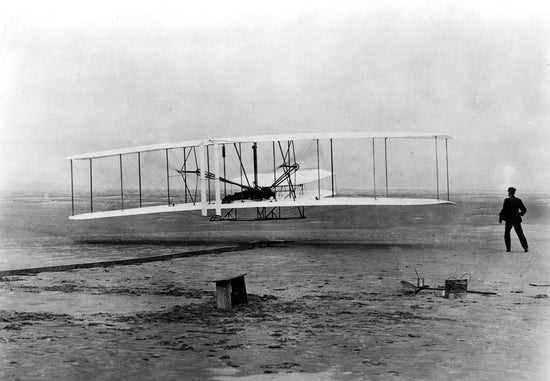 The Wright brothers, Orville Wright and Wilbur Wright flying an airplane in Kitty Hawk, North Carolina.